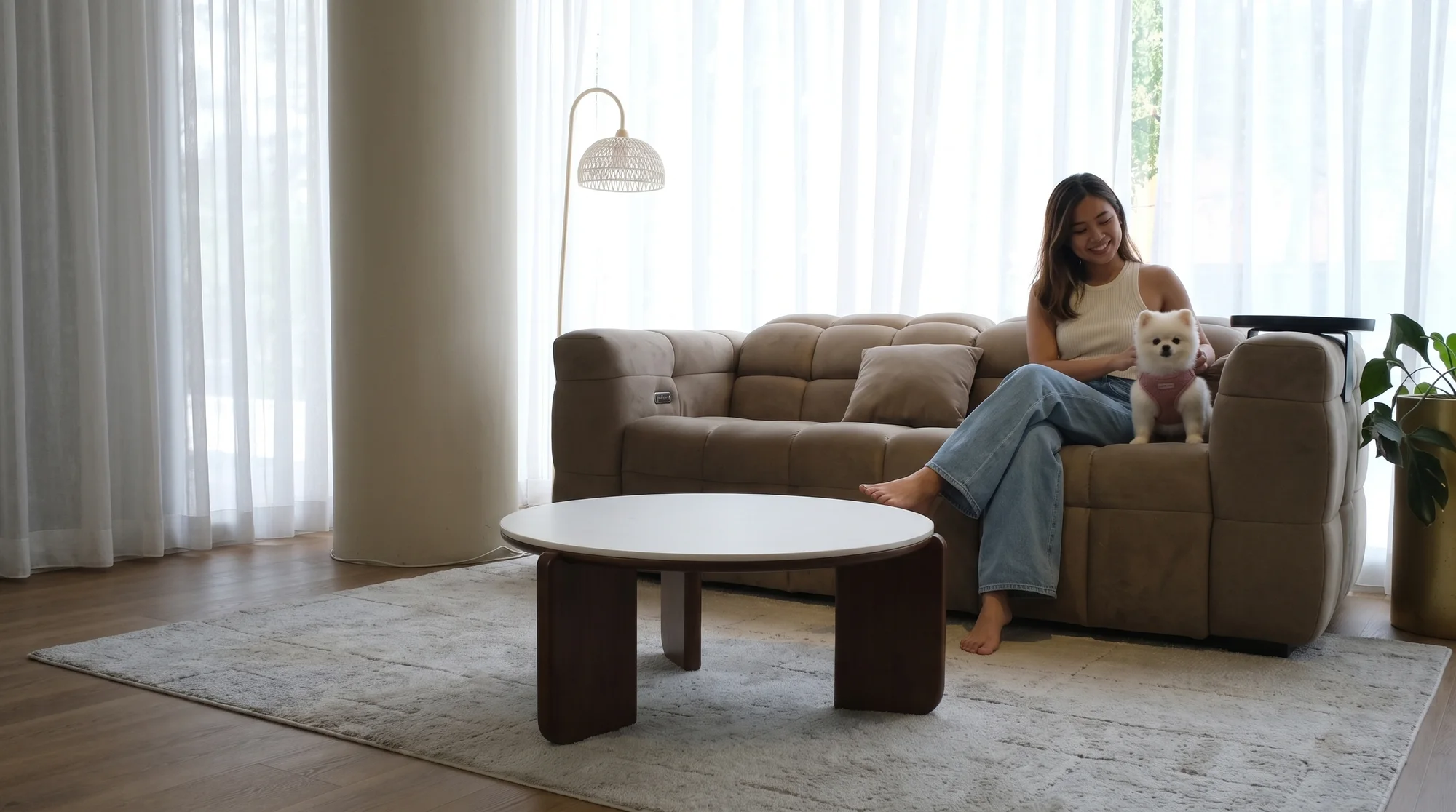 A customer sitting on a Son&Bear sofa in the Singapore showroom with her small dog beside her.